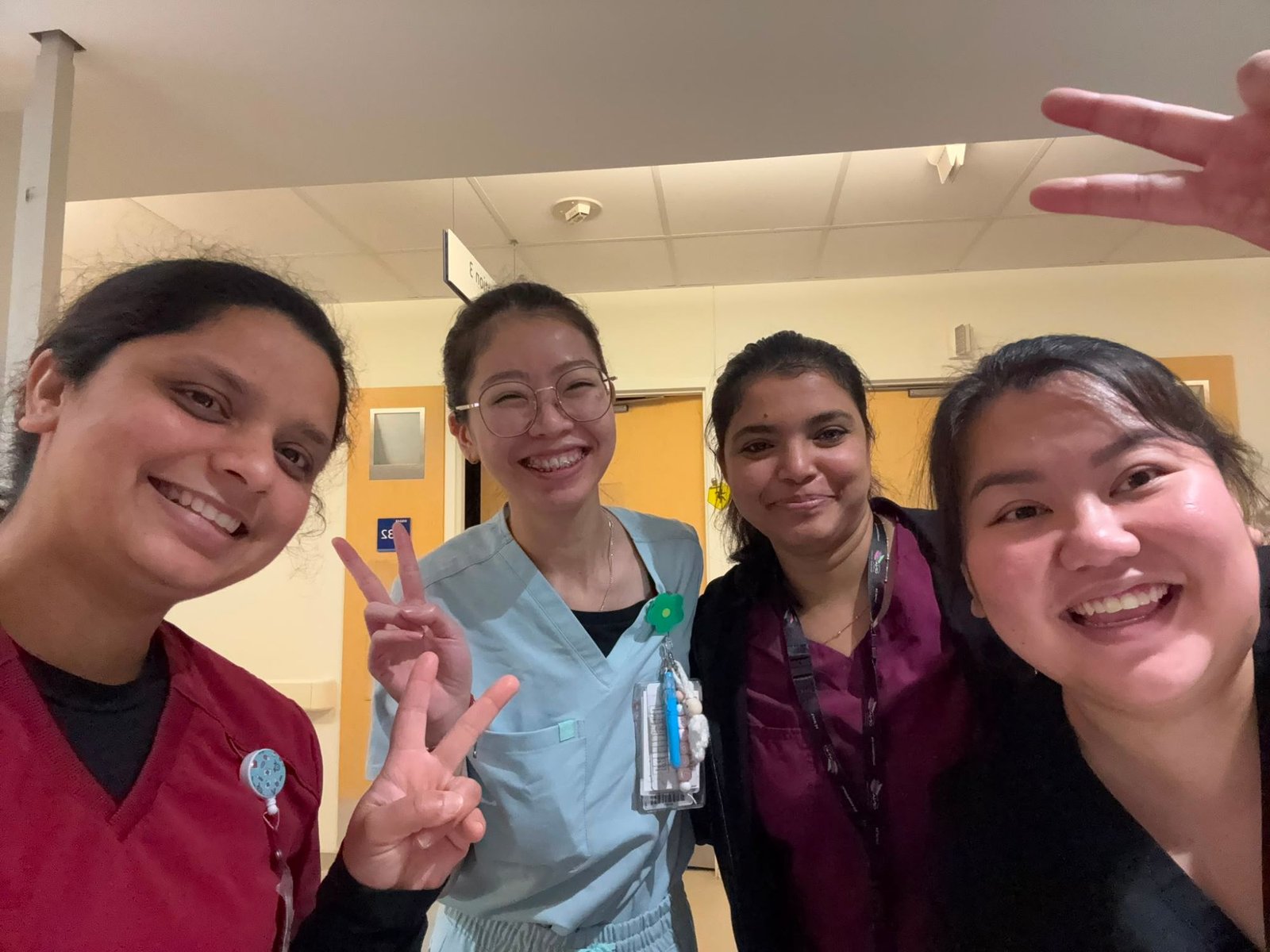 Four team members sharing a laugh in a hospital corridor