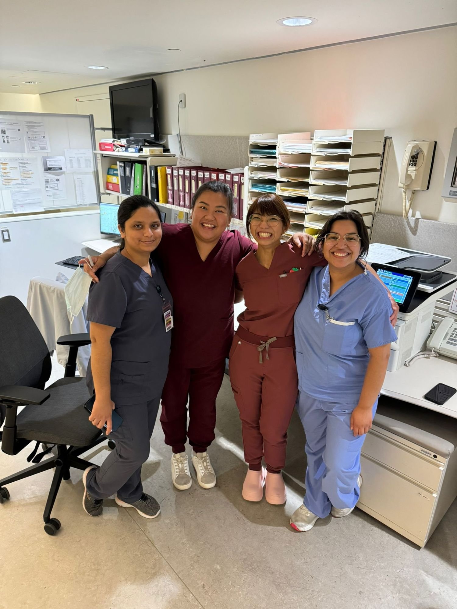 Four team members, arms around each other, at a nursing station